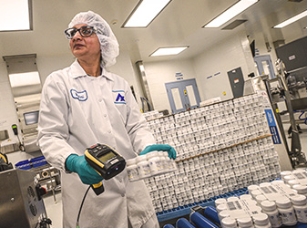 Women in production line checking bottle pills