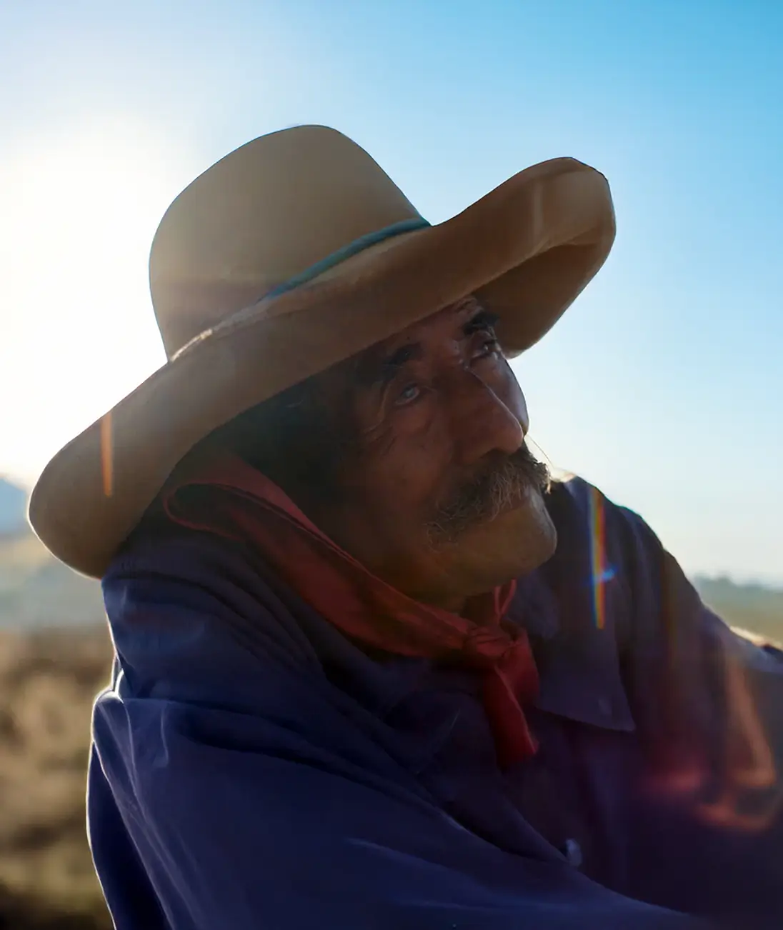 Elderly man in a wide-brimmed hat outdoors, lit by the sun
