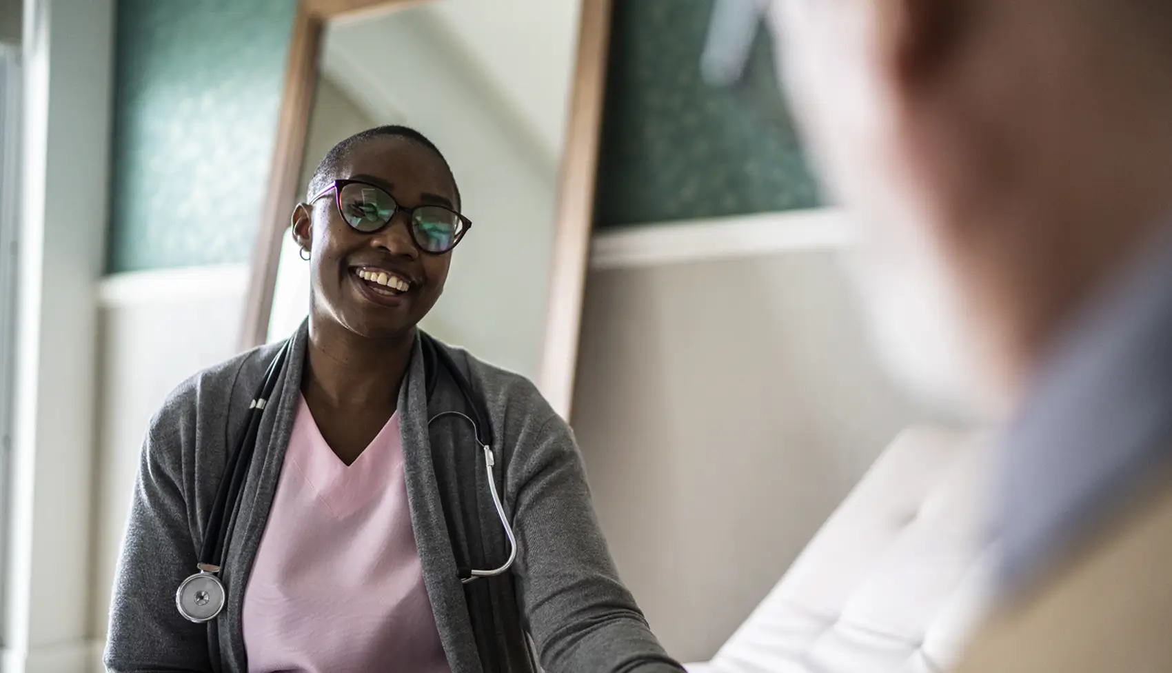 Smiling healthcare professional with stethoscope talking to a patient.