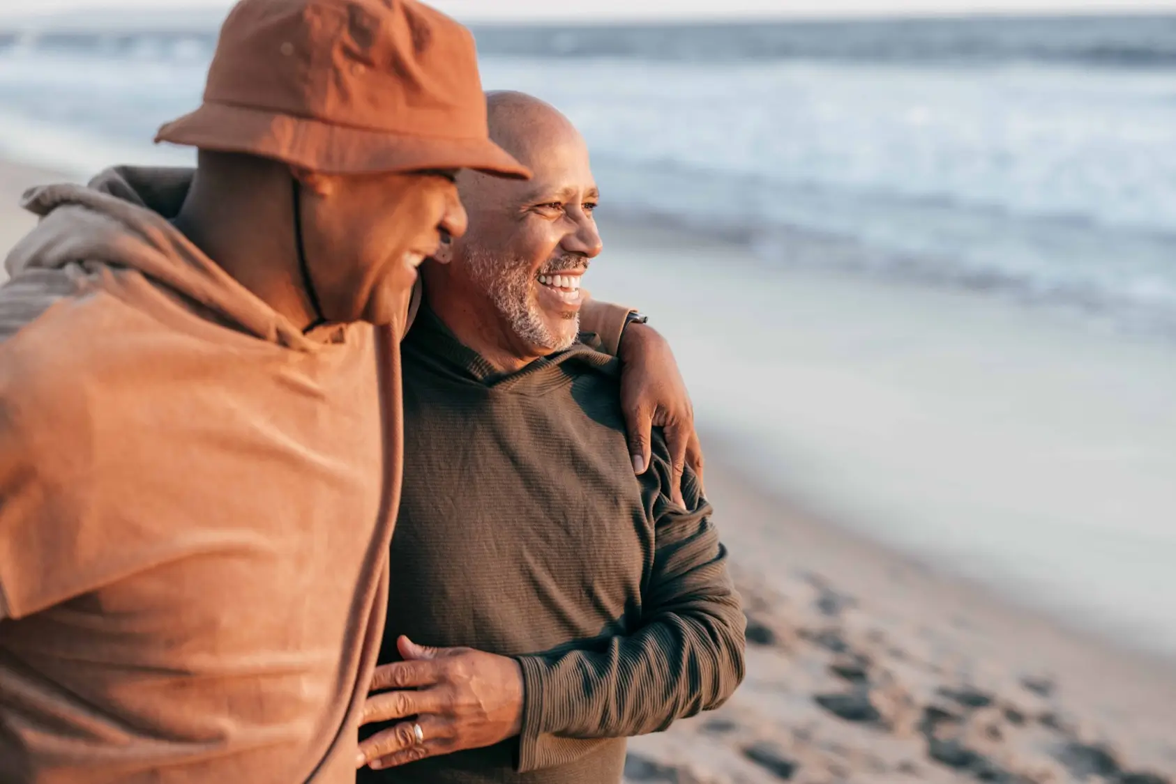Two men hugging and smiling on the beach