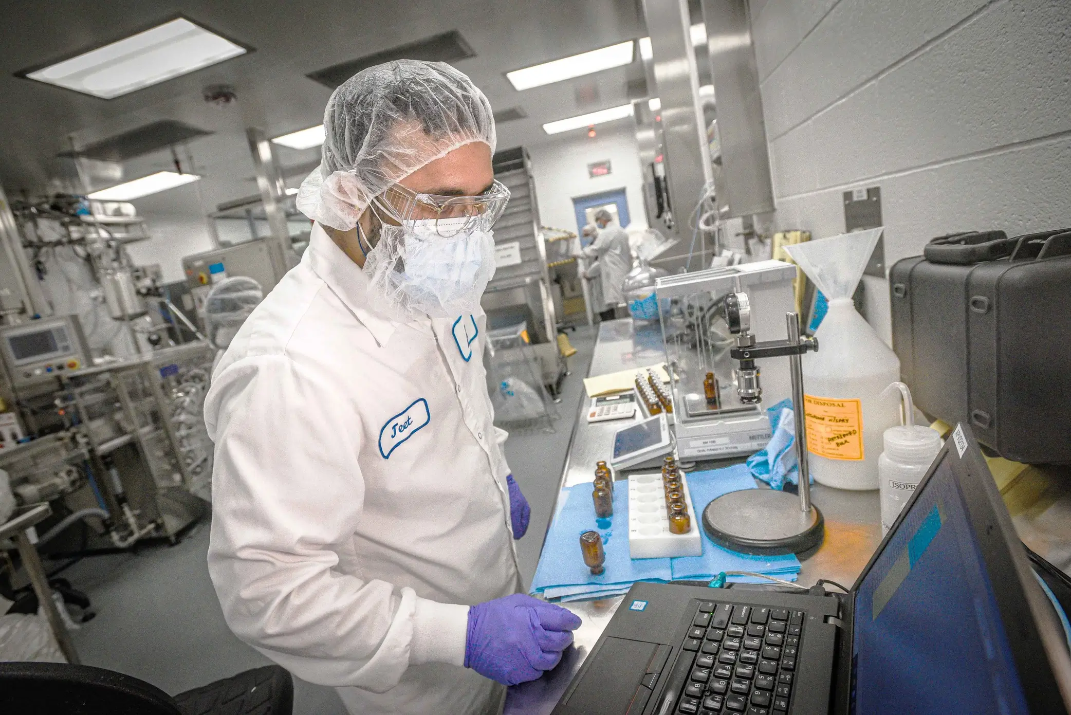 Scientifique travaillant avec des fioles et un ordinateur portable dans un laboratoire