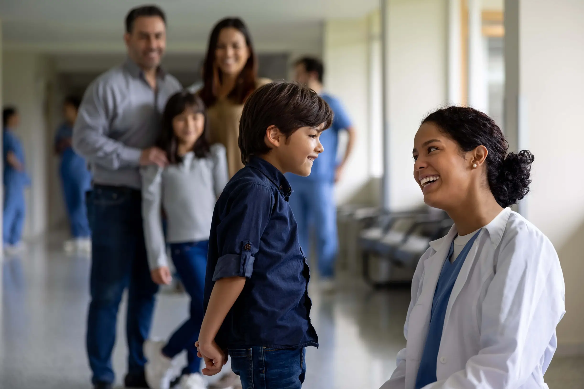 Professionnel de la santé souriant avec un enfant et sa famille en arrière-plan