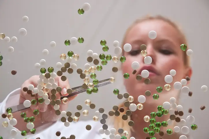 A person using tweezers to manipulate small, colorful spheres A person using tweezers to manipulate small, colorful spheres
